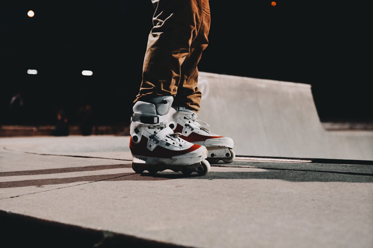 A person wearing inline skates on a concrete surface at a skate park during nighttime.