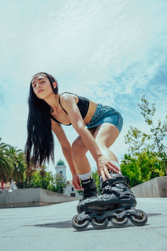A young brunette woman roller skating outdoors, showcasing skill and fashion on a sunny day.