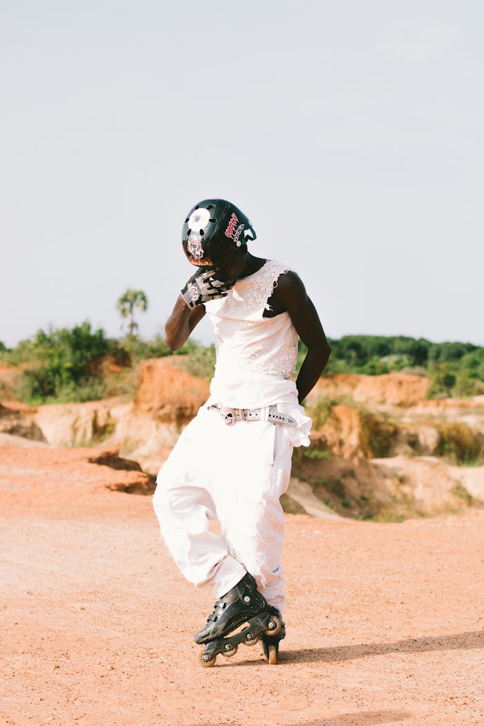 A skater in a white outfit performing outdoors on a rough terrain.