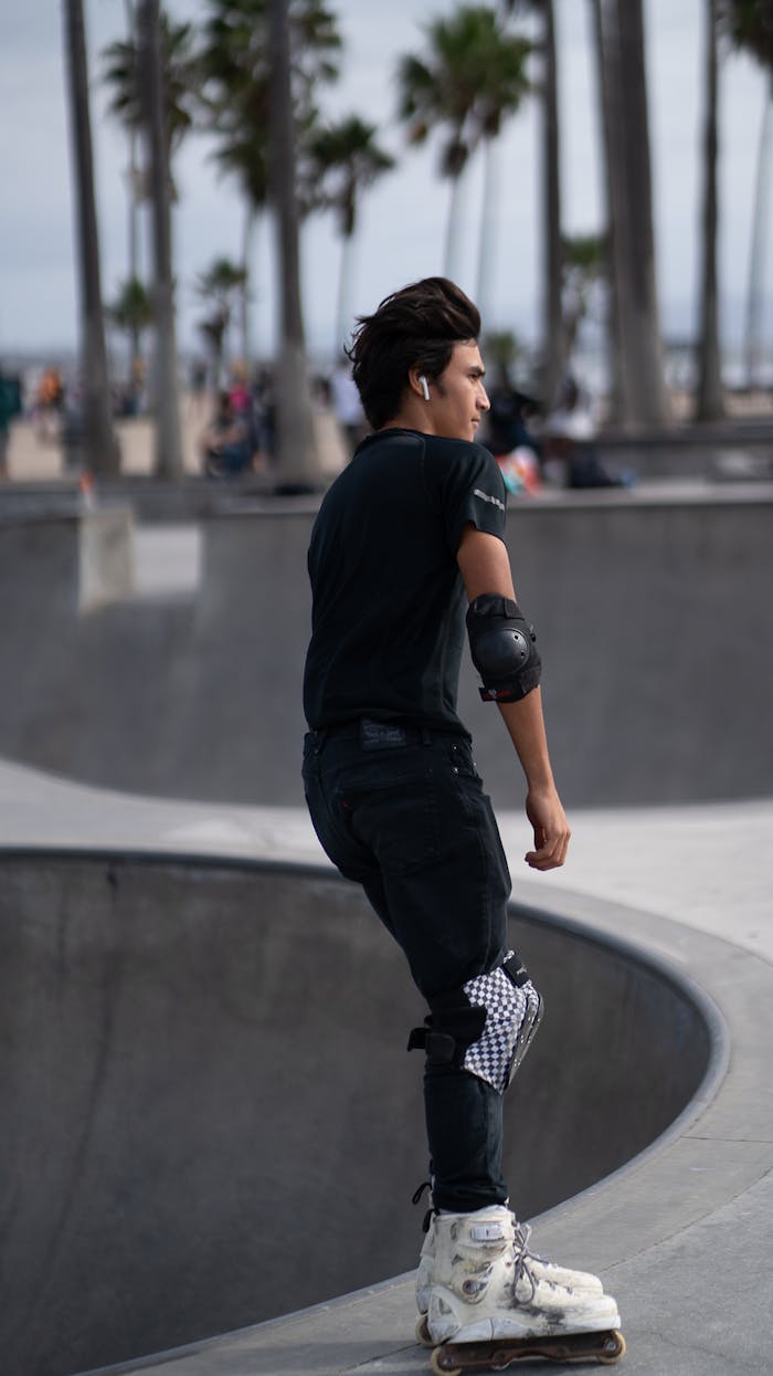 Teenager skating in Venice Beach park wearing protective gear, showcasing youth and freedom.